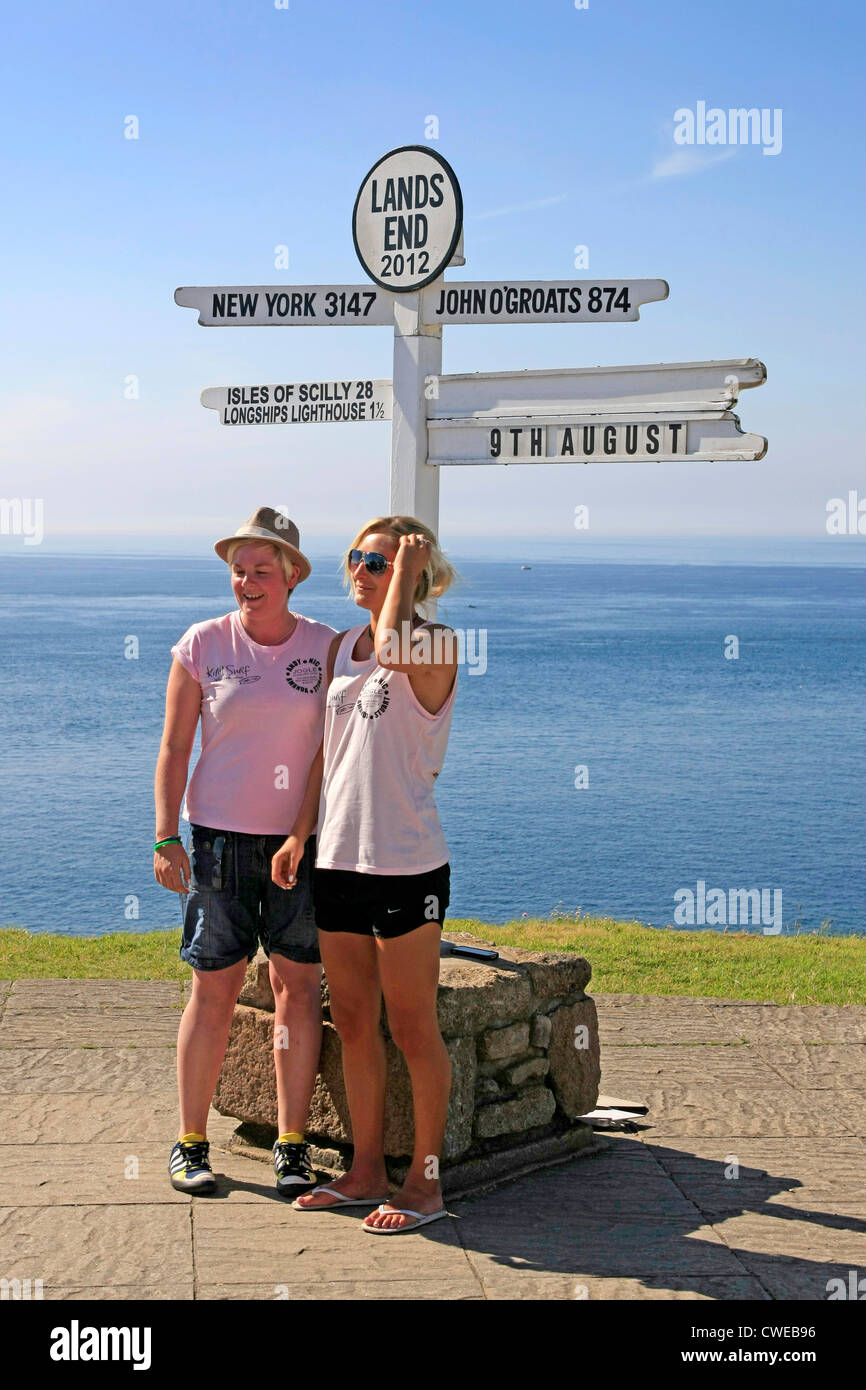 Two women pose under the famous Lands End sign in Cornwall England Stock Photo