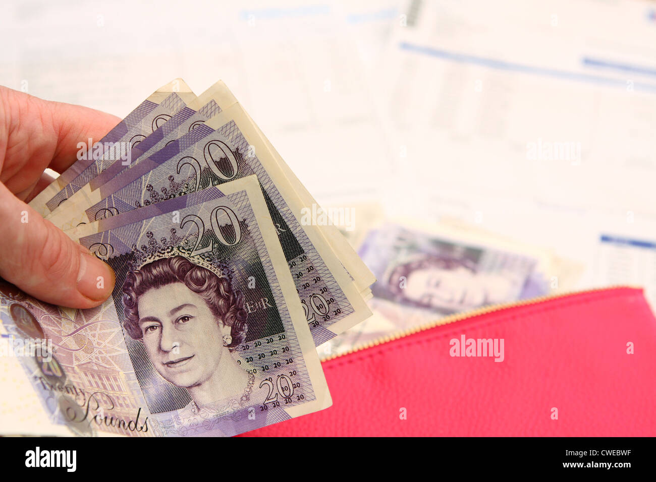 a hand holding £20 notes with with a purse, a £20 note and other out of ...
