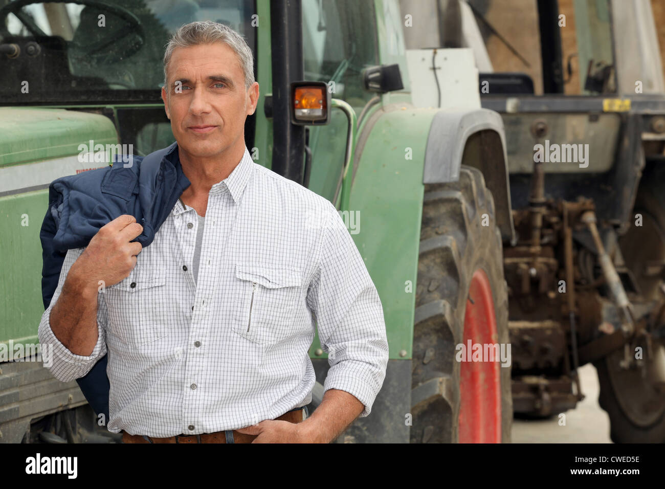 farmer posing in front of his tractor Stock Photo - Alamy