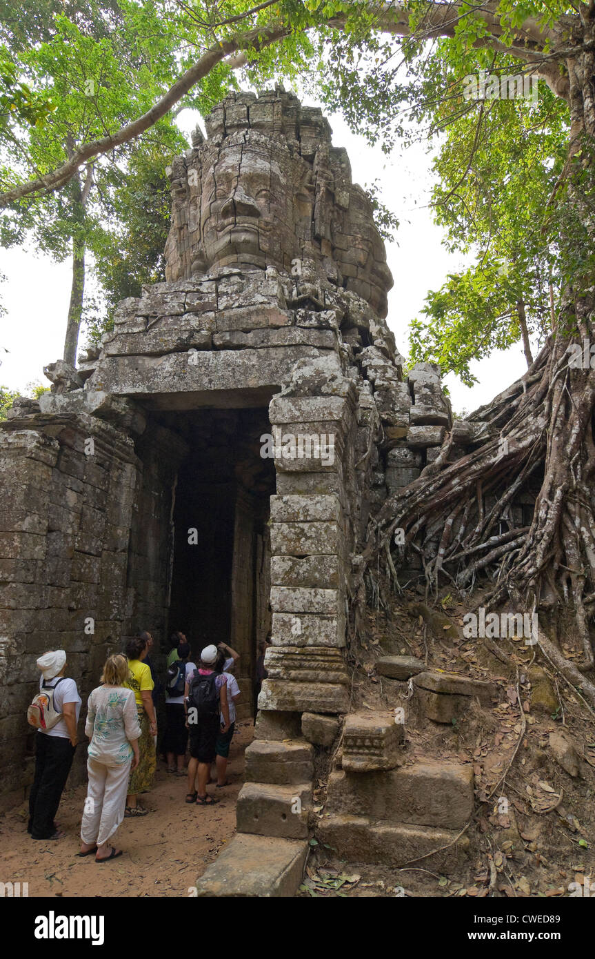 Vertical view of one of the stone faced gopura entrances to Ta Prohm or the Tomb Raider temple with tourists walking through. Stock Photo