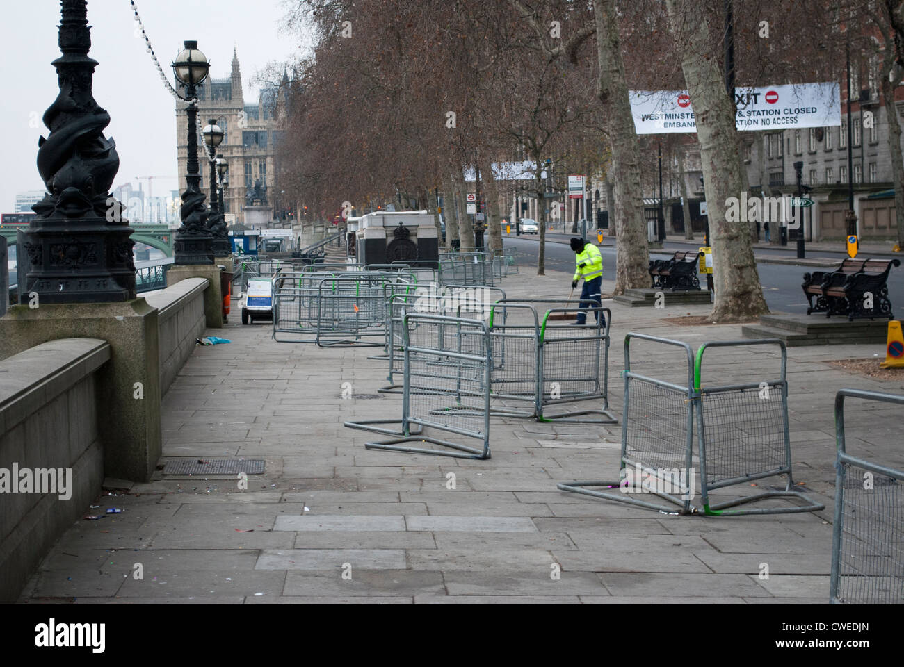 Man in yellow hi-viz jacket clearing away pedestrian barriers on Victoria Embankment on the New Year's Day morning Stock Photo