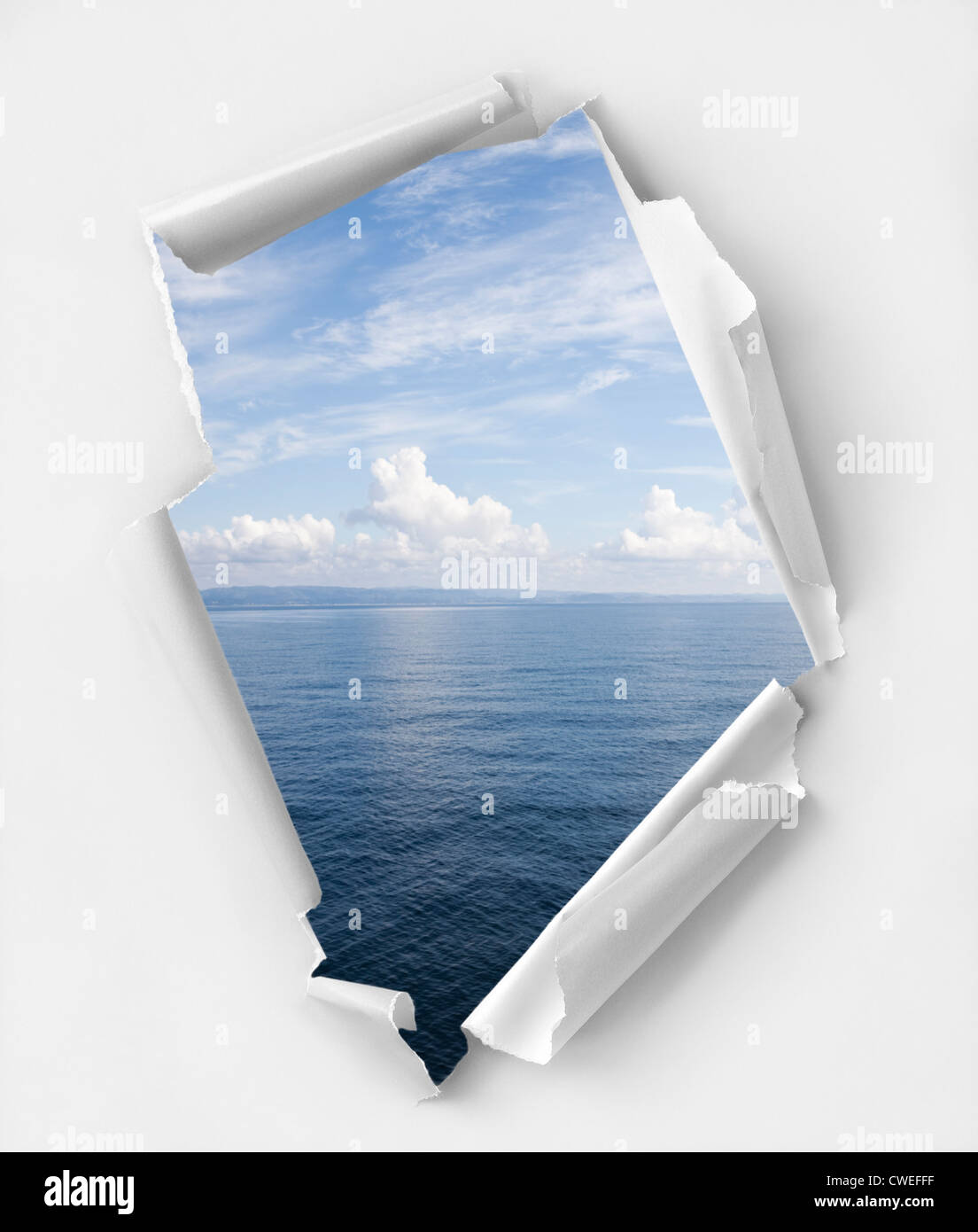Hole ripped paper with a relaxing seascape. Clipping path inside hole Stock Photo