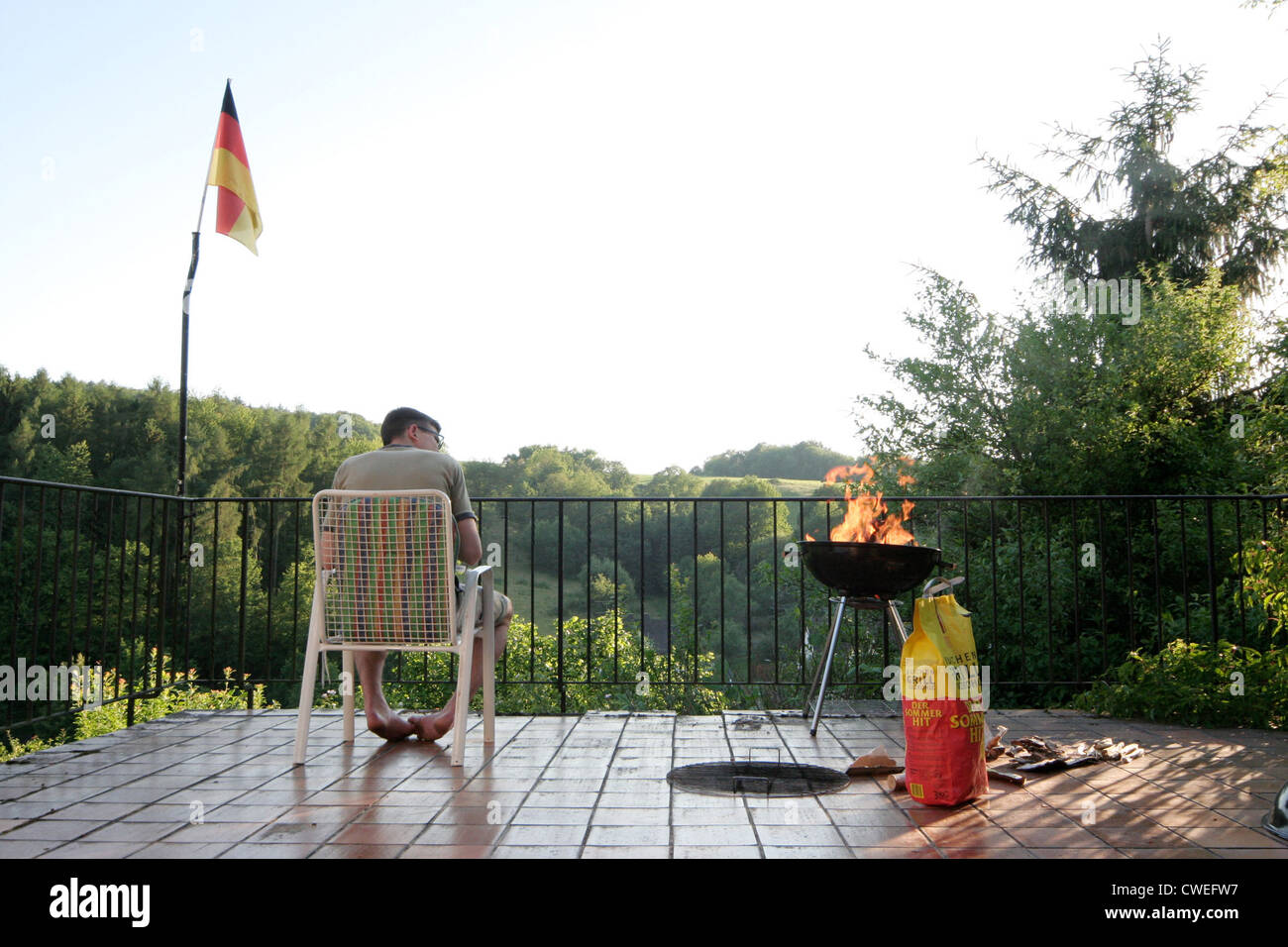 Young man sitting on a terrace and looking for the grill Stock Photo