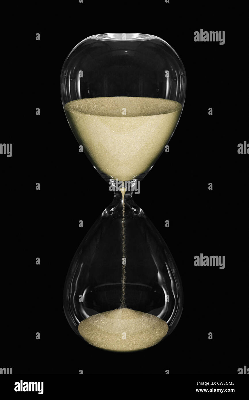 An hourglass showing the sands of time passing isolated on a black background Stock Photo