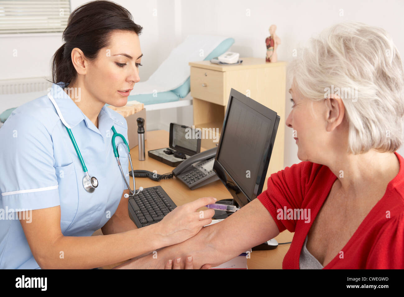 British nurse giving injection to senior woman Stock Photo