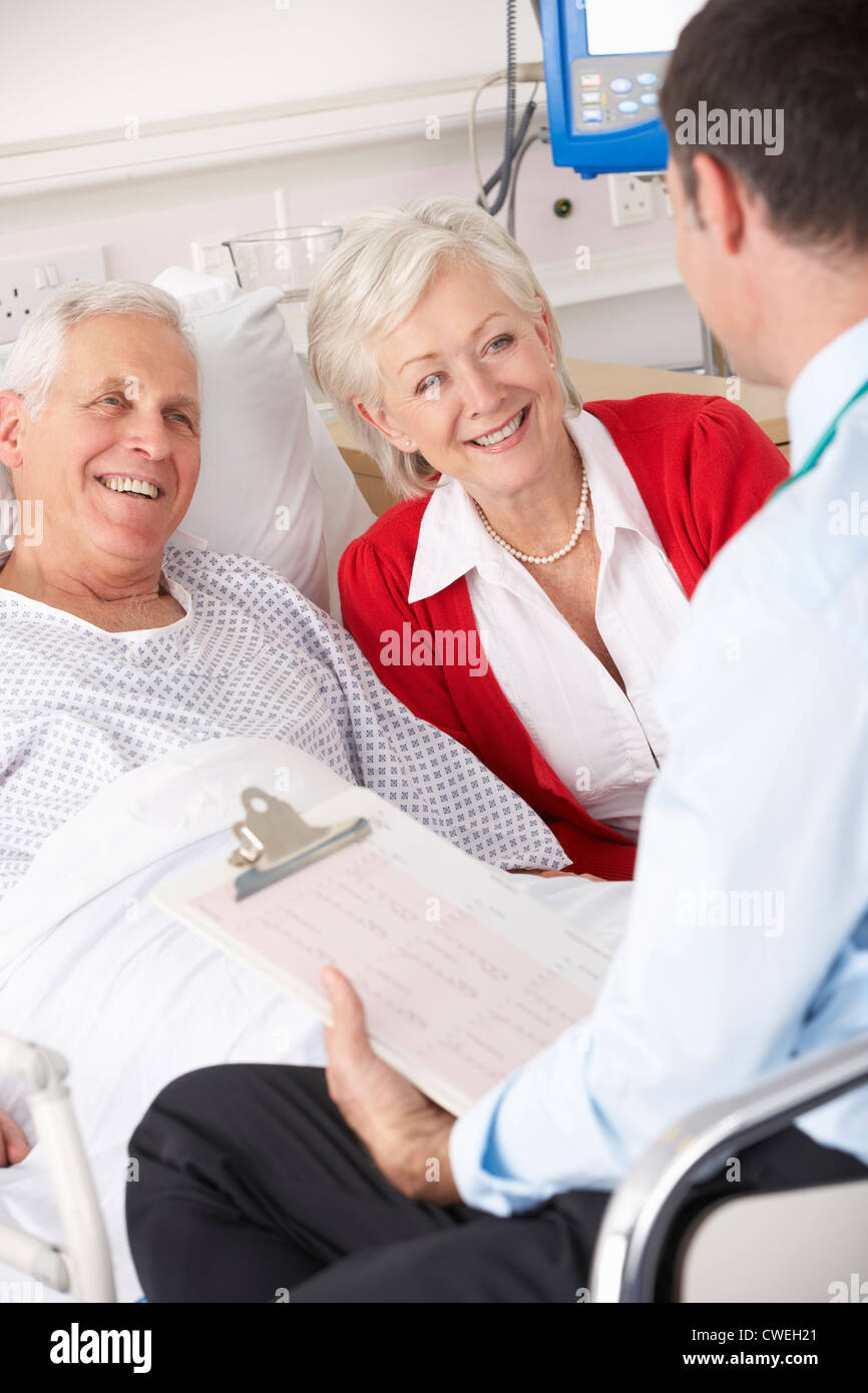 Doctor talking to senior couple on UK Hospital ward Stock Photo