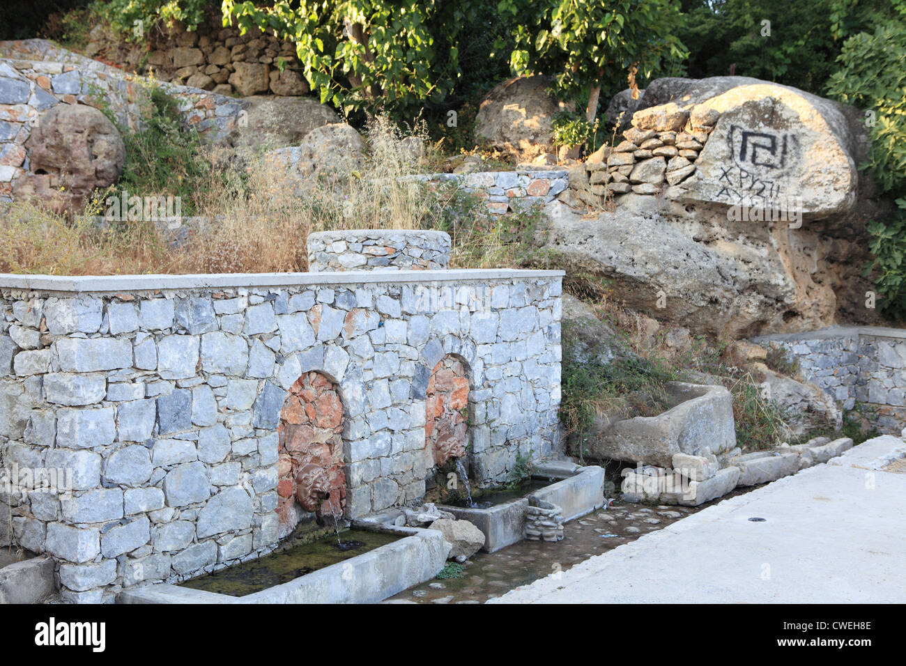 An old village spring in Crete with fascist 'Golden Dawn' graffiti sprayed on a rock in the background Stock Photo