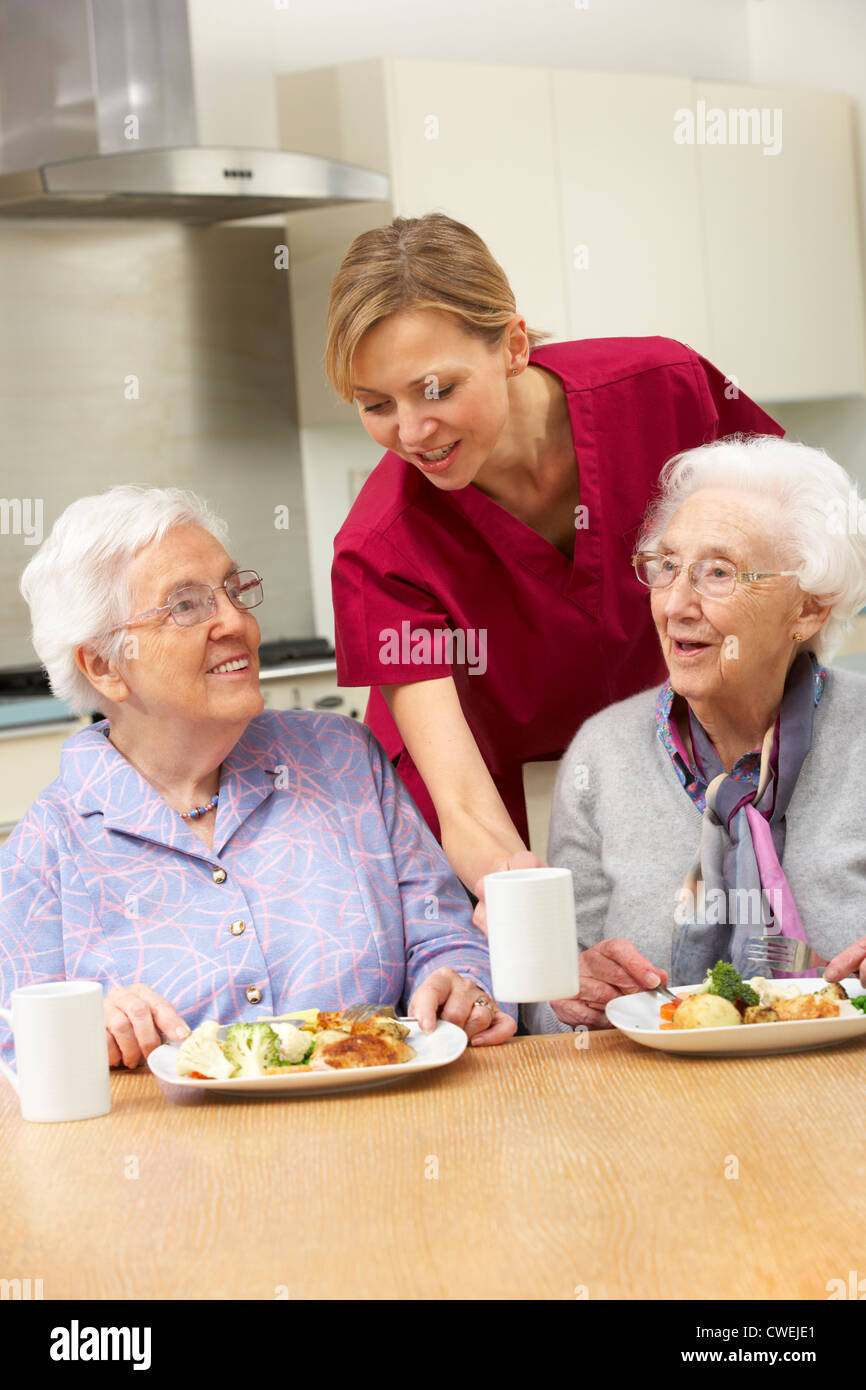 Senior women with carer enjoying meal at home Stock Photo