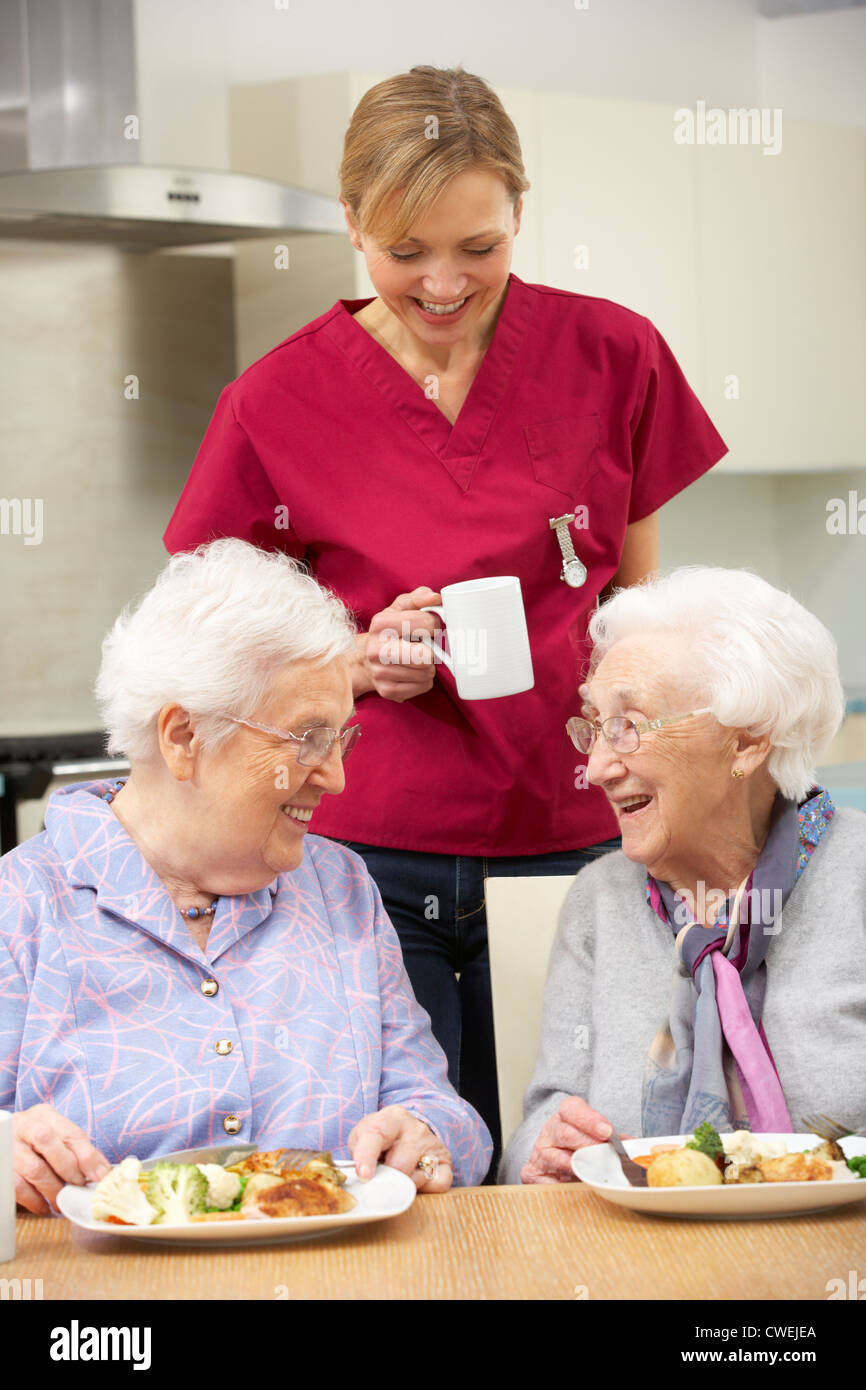 Senior women with carer enjoying meal at home Stock Photo