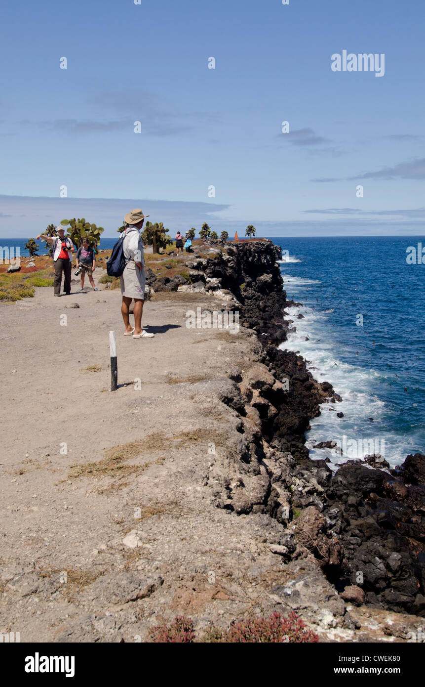 Ecuador, Galapagos, South Plaza Island. Tourists hiking around the rocky volcanic coast of South Plaza. Stock Photo
