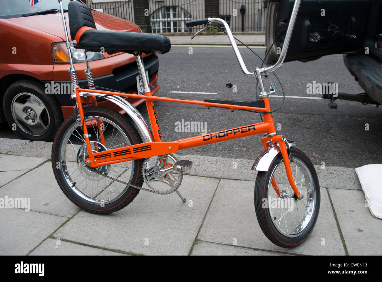 Orange Raleigh Chopper bicycle parked on stone flagged pavement outside Tate Britain before New Years Day procession Stock Photo