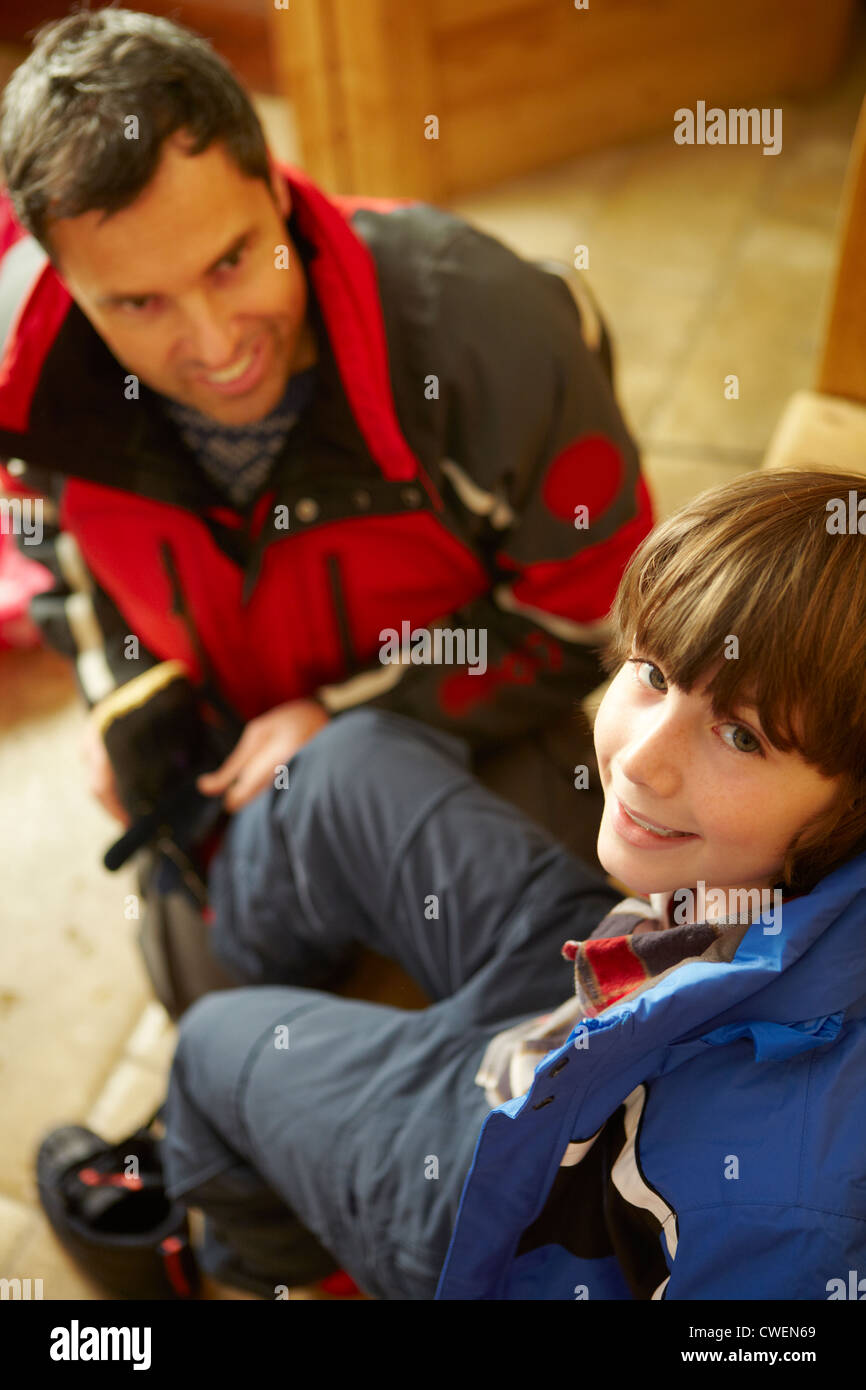 Father Helping Son To Put On Warm Outdoor Clothes And Boots Stock Photo