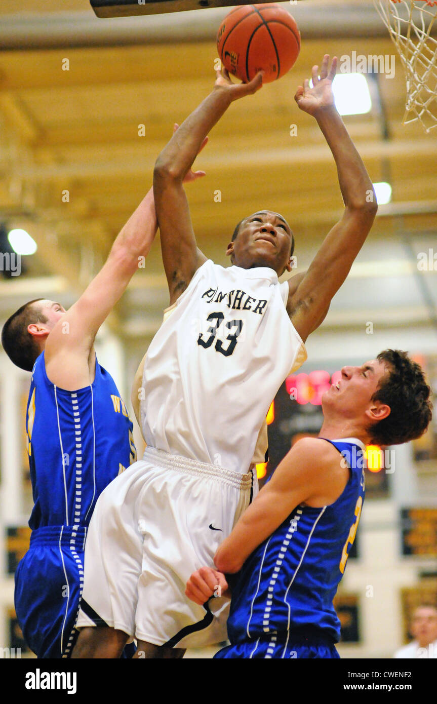 Basketball player shooting between two defenders during a high school