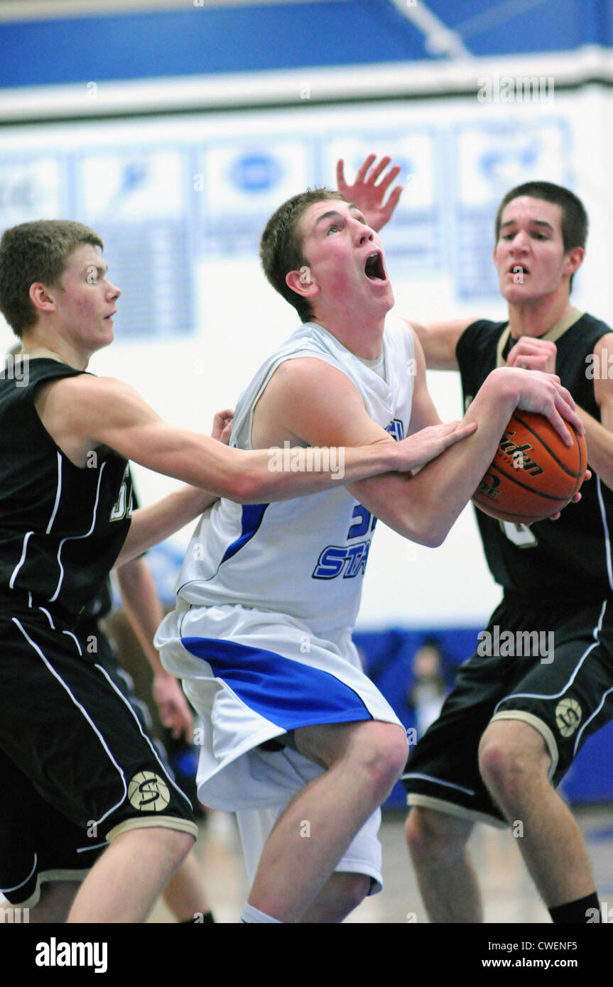 Basketball player tries to split the defense and is fouled for his effort during a high school game. Stock Photo