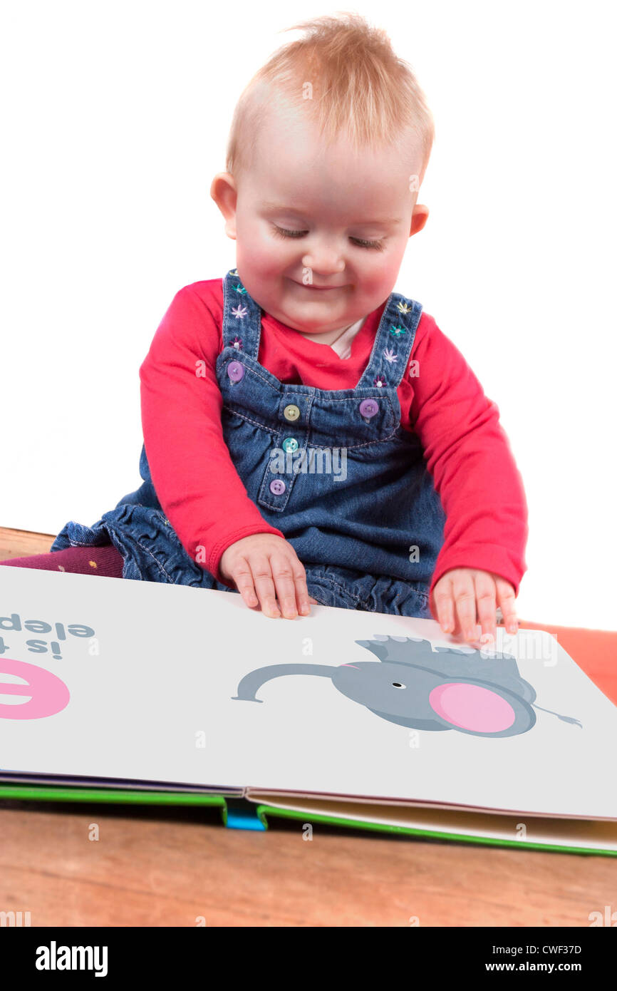 cute little baby girl reading a big book whilst sitting on the floor Stock Photo
