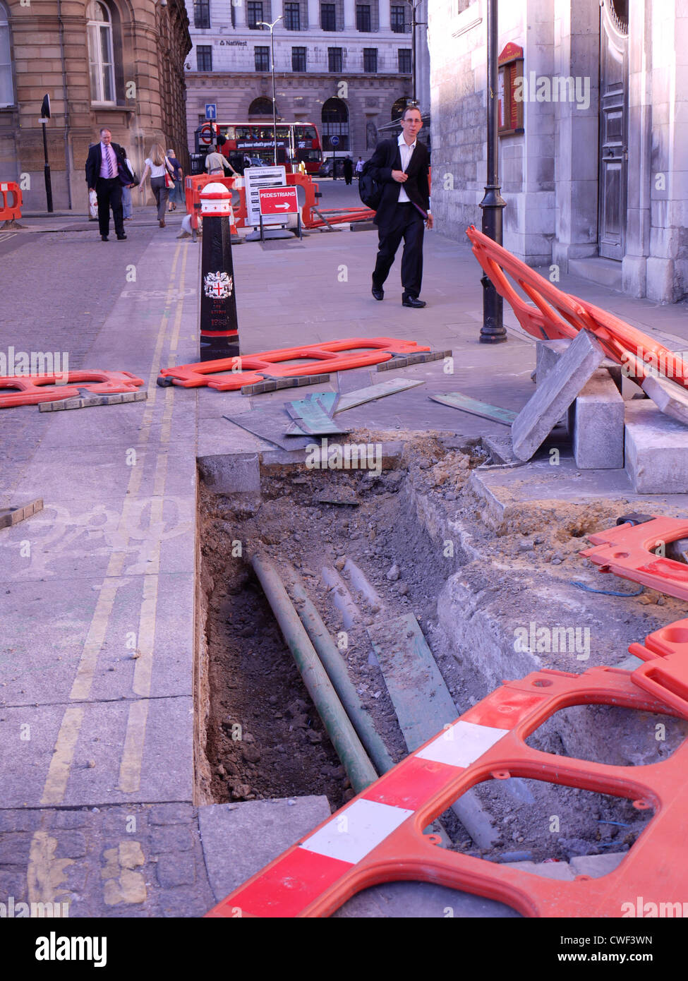 road-works-hole-in-road-with-cables-and-knocked-over-safety-barriers-CWF3WN.jpg