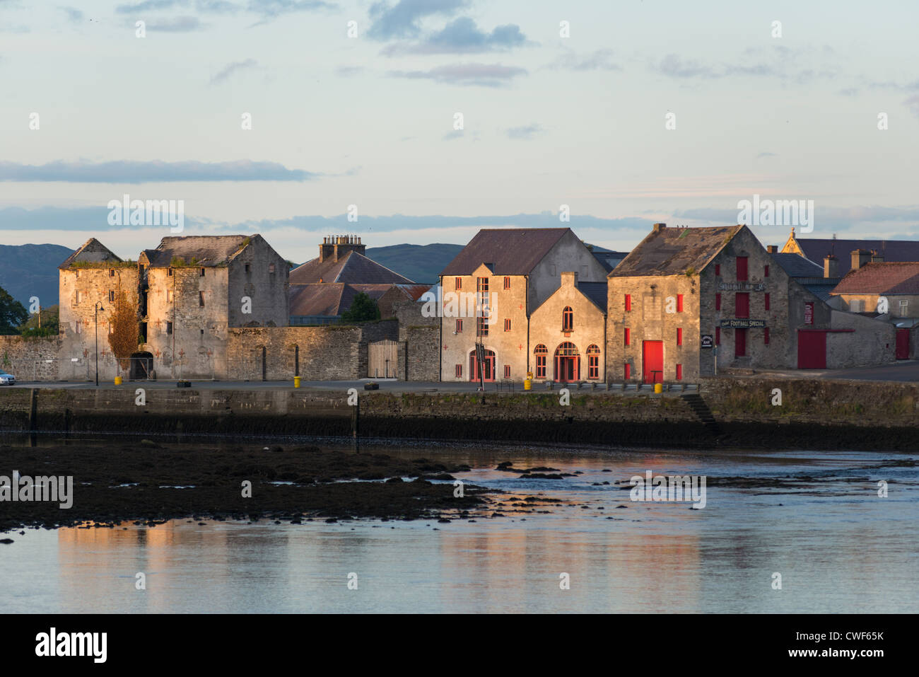 Man fishing with view of warehouses on the waterfront, Rathmelton, County Donegal, Ulster Province, Republic of Ireland. Stock Photo