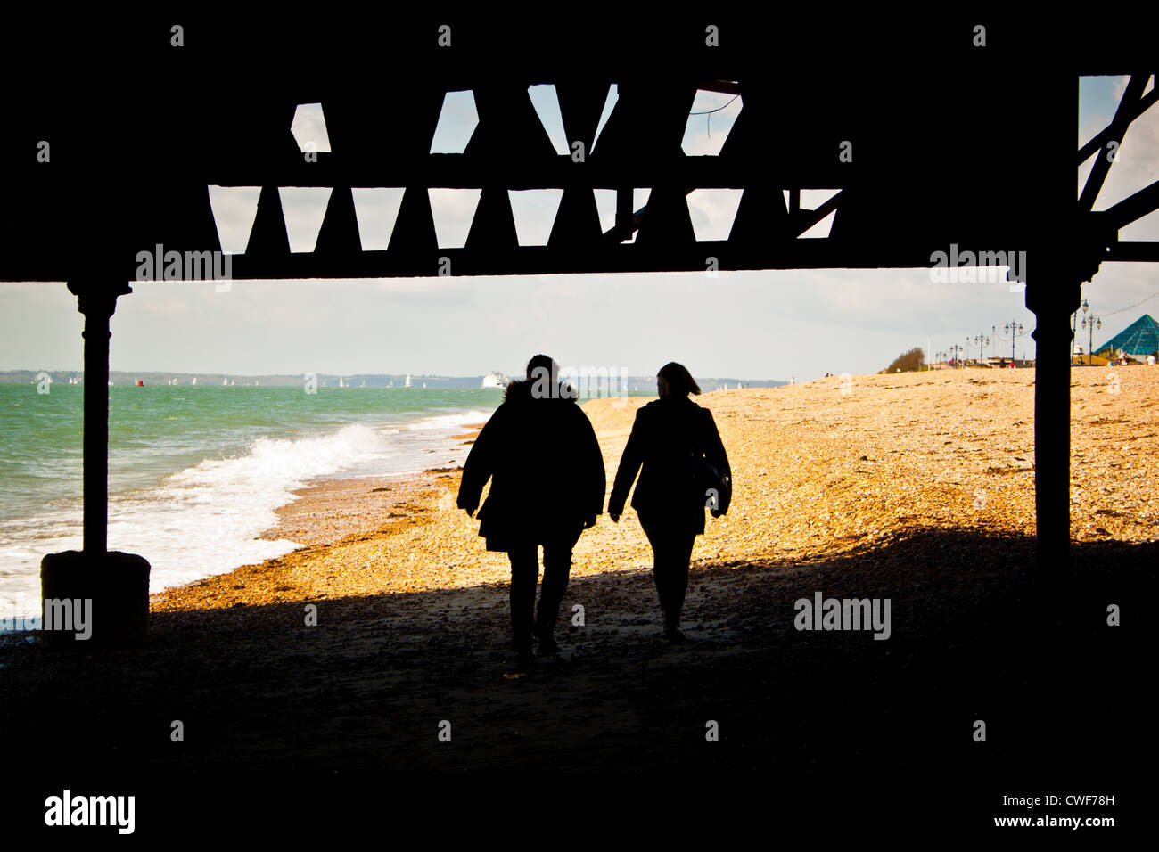 The silhouette of two ladies walking beneath the decaying South Parade Pier, Southsea, Portsmouth, United Kingdom Stock Photo