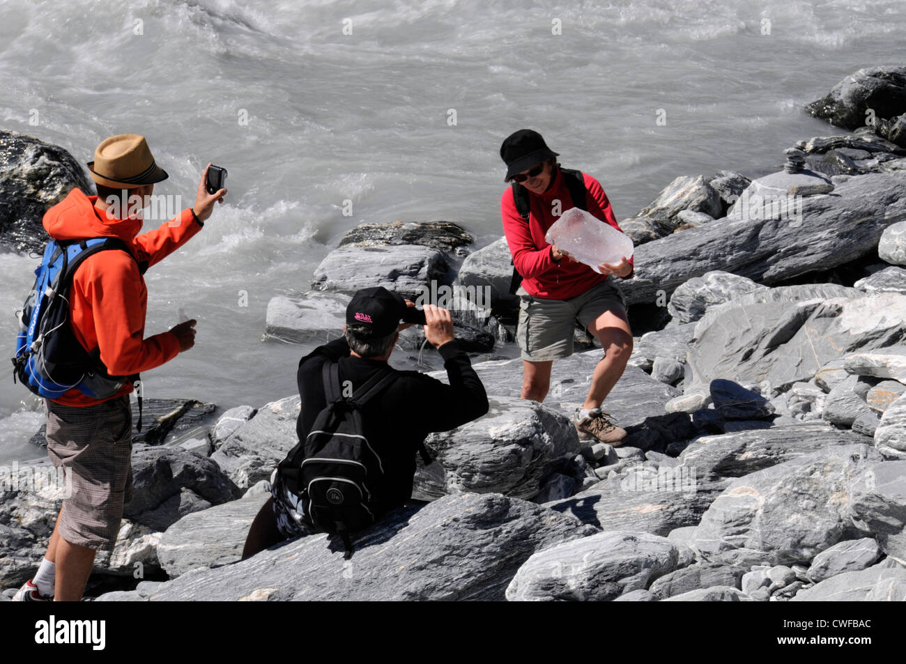 A young visitor poses for the camera, holding a block of ice (serac) found in the fast-flowing river at Franz Josef Glacier at the foot of he 12 km Stock Photo