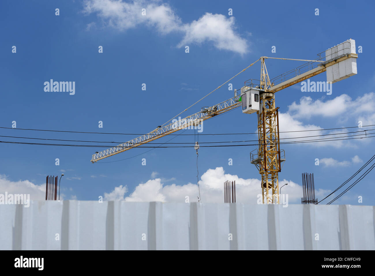 The crane is building construction behind the fence. Stock Photo