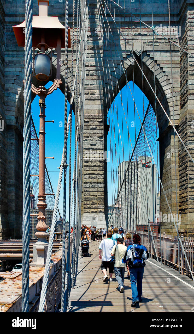 NEW YORK CITY-MAY 31, 2009: People walking across the Brooklyn Bridge in New York City. Manhattan skyline is in the background. Stock Photo