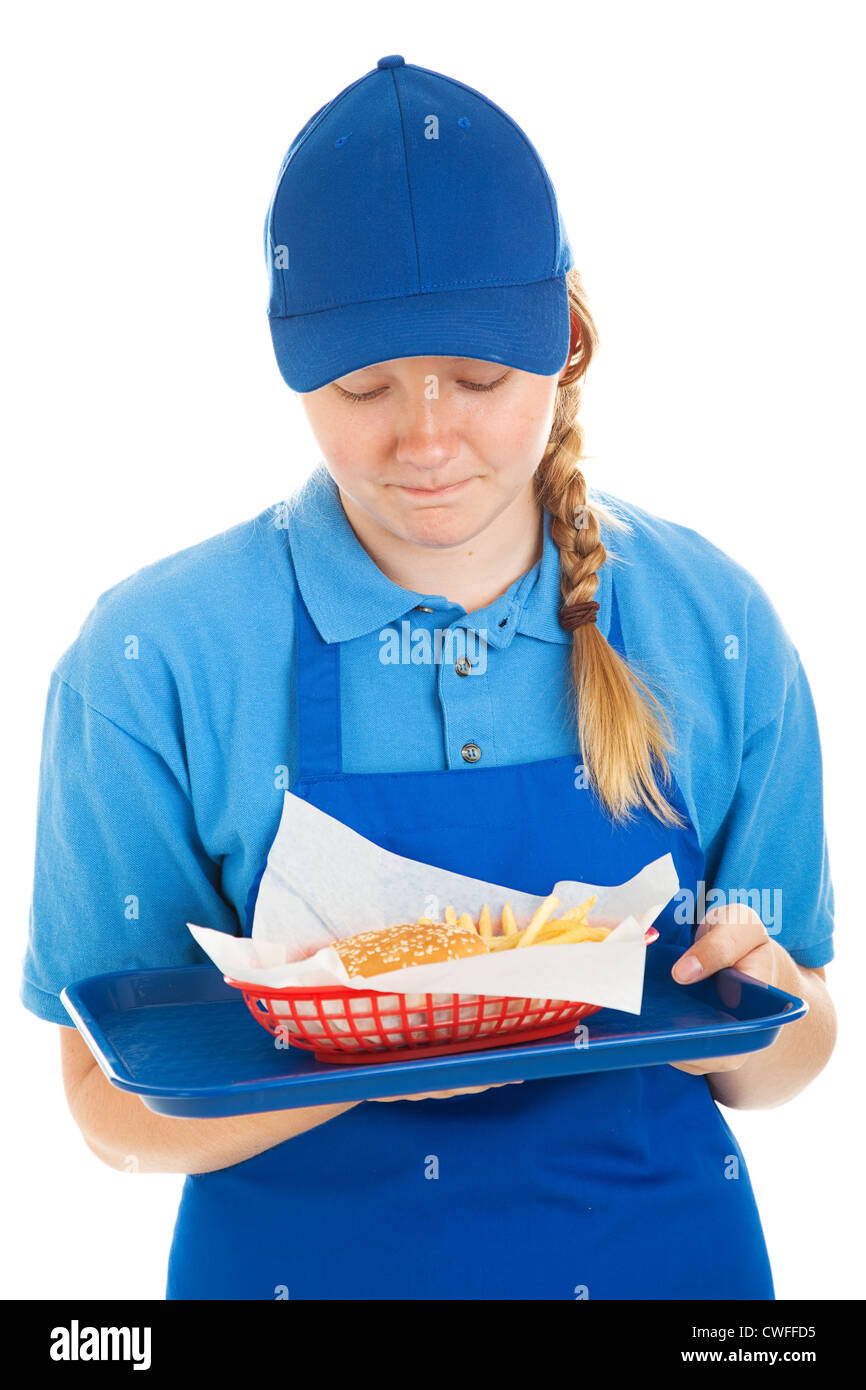 Teenage fast food worker disgusted by the burger and fries she's serving. Isolated on white. Stock Photo