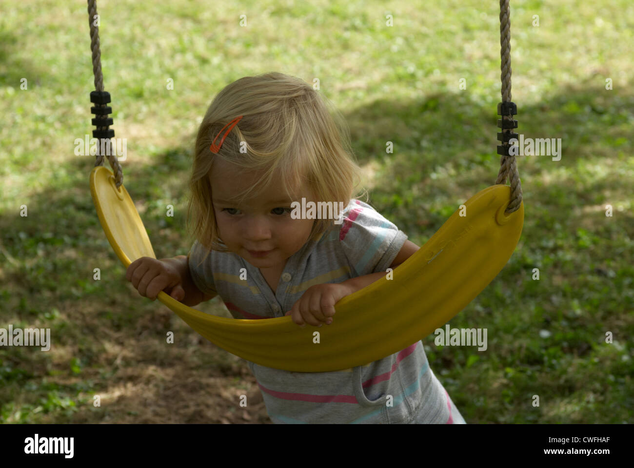 Blond girl having a swing outside summer Stock Photo