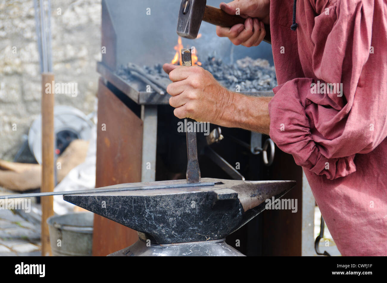 Blacksmith smithies with a big sledgehammer, chisel on anvil a iron