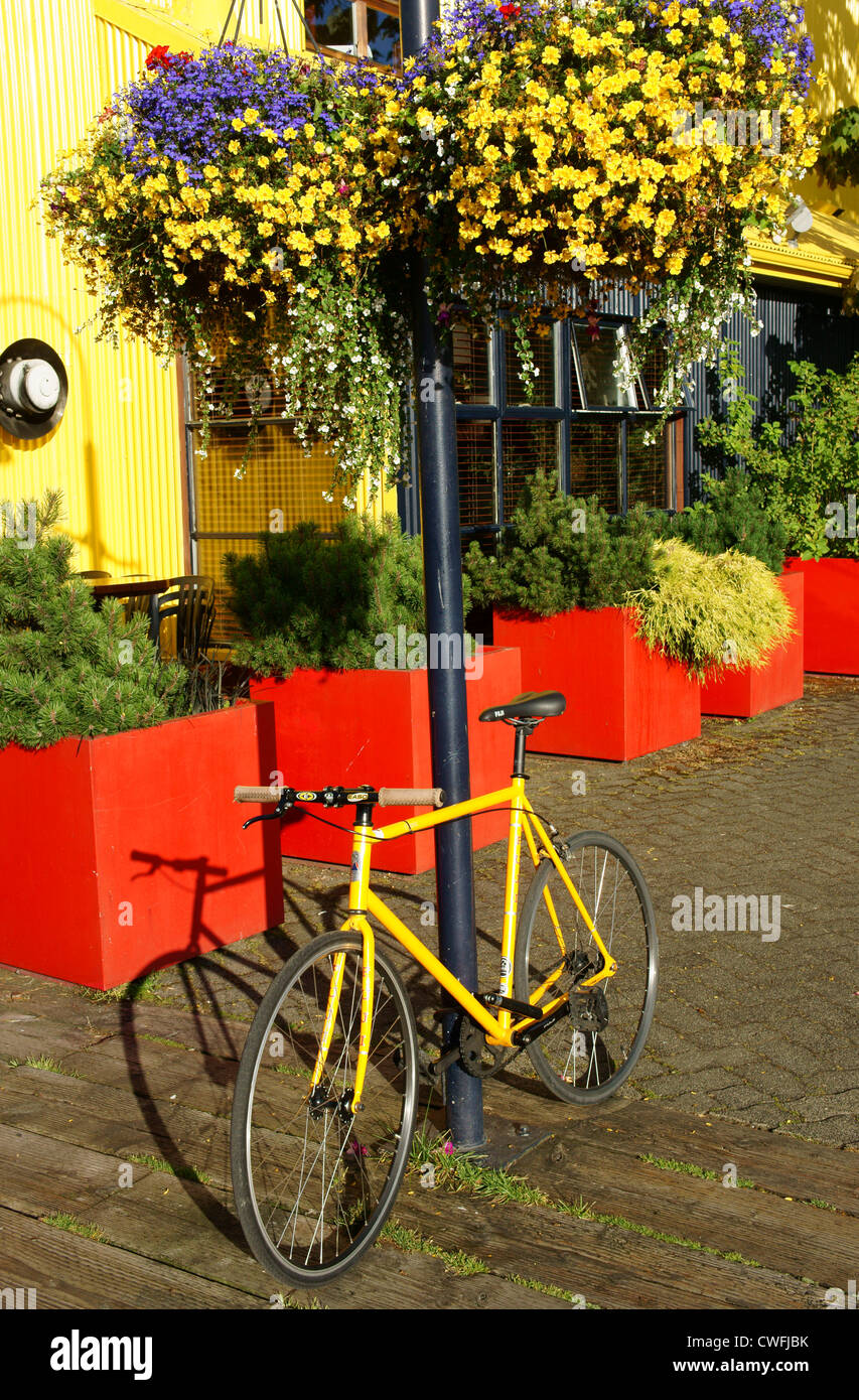 Yellow bicycle and hanging flowers. Granville Island, Vancouver, British Columbia, Canada Stock