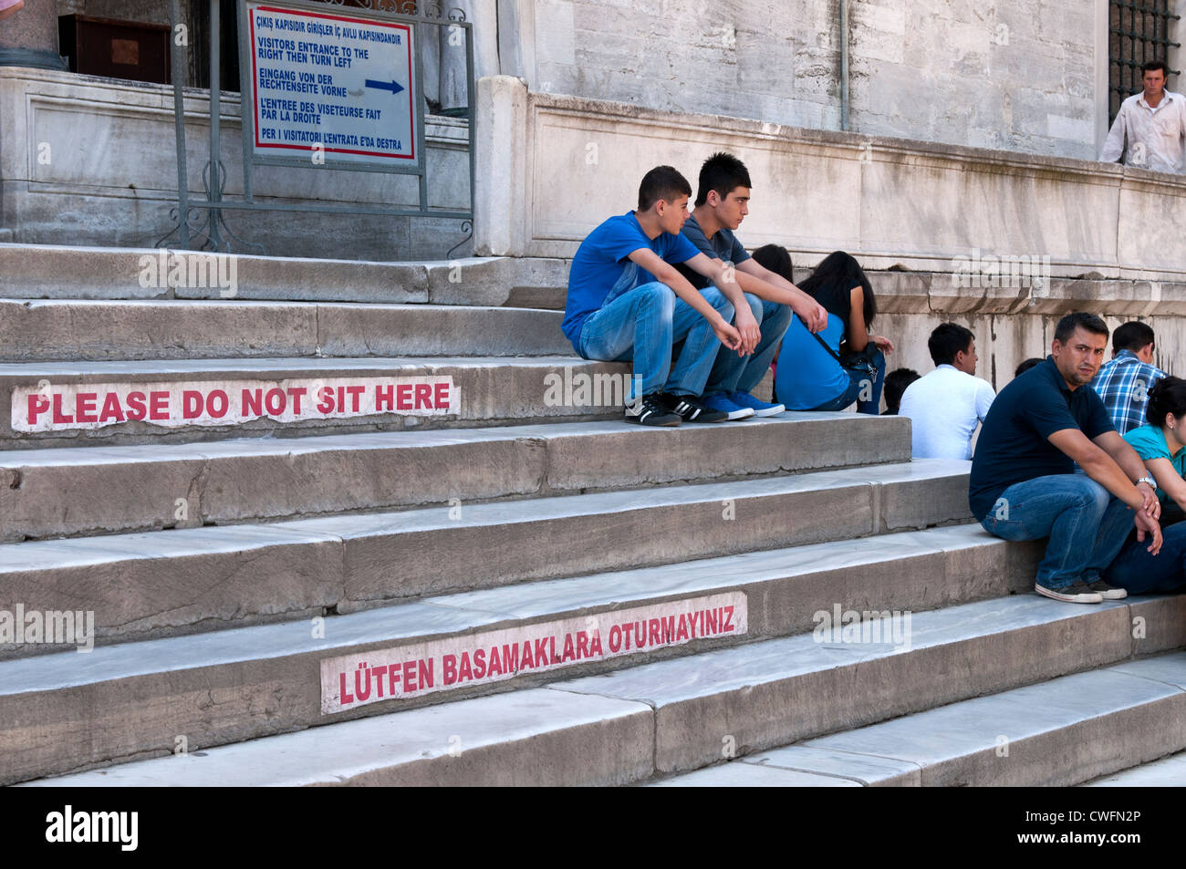 People sitting on the entry steps to the Blue Mosque, Sultanahmet, Istanbul, Turkey Stock Photo