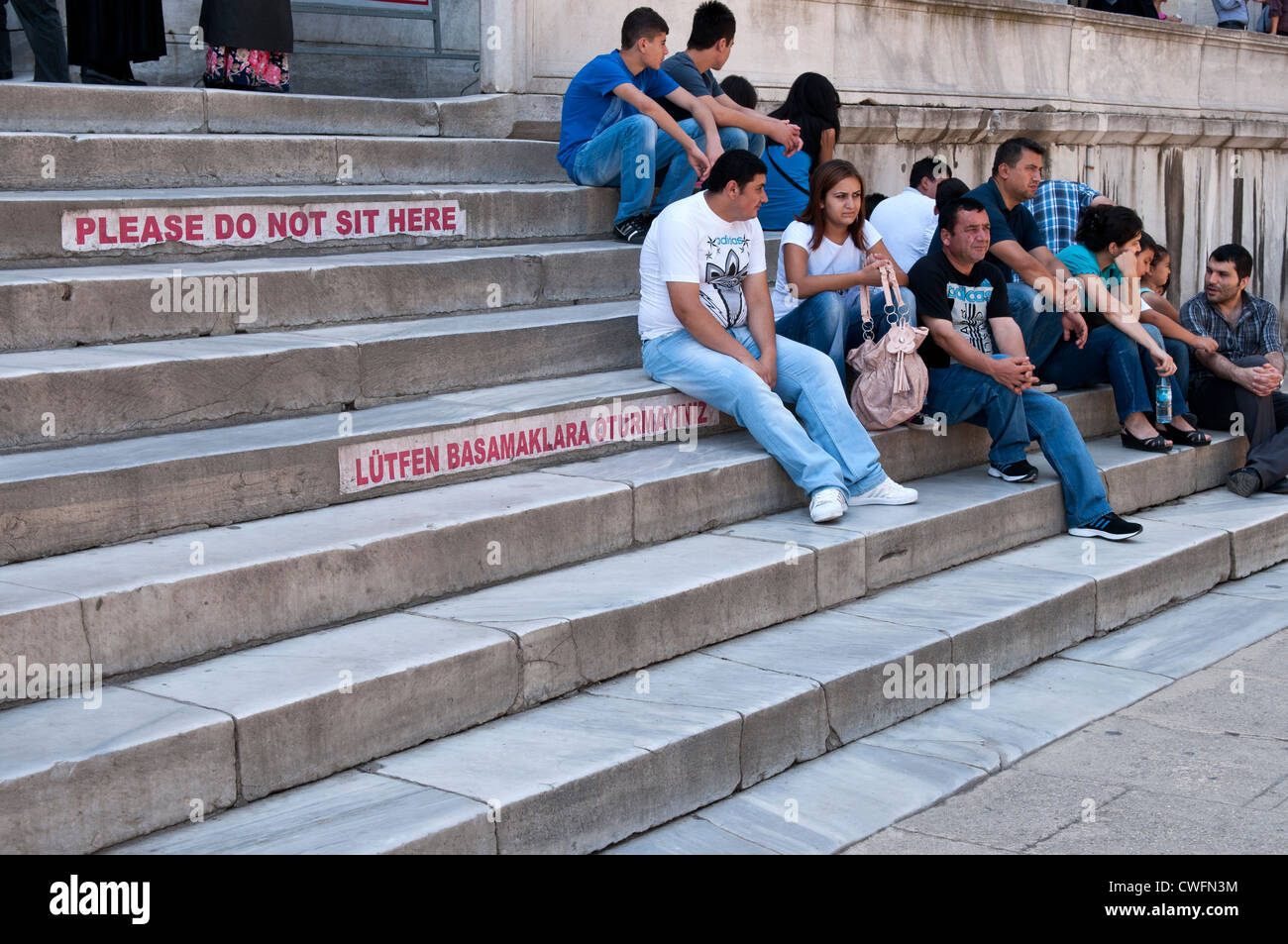 People sitting on the entry steps to the Blue Mosque, Sultanahmet, Istanbul, Turkey Stock Photo