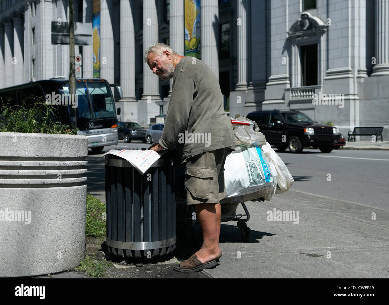 Montreal - A homeless man reads a newspaper in a trash Stock Photo
