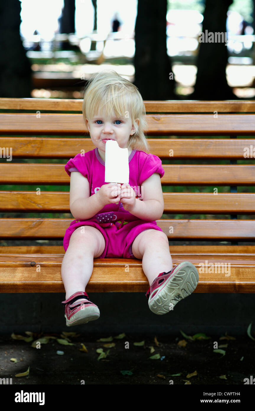 One year old baby girl eating ice cream at the park Stock Photo