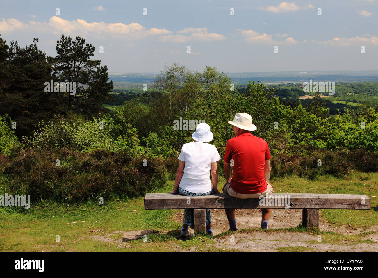 Man and woman resting on the bench at the top of the Devil's Punch Bowl, Surrey Hills, England Stock Photo
