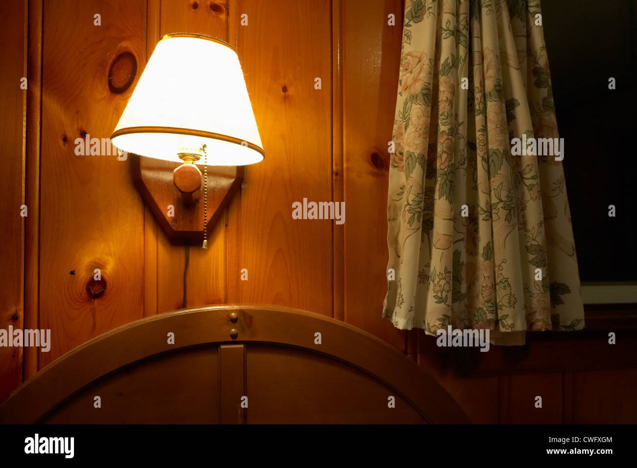 Shaded Lamp On A Wood Paneled Wall With Curtains Stock Photo