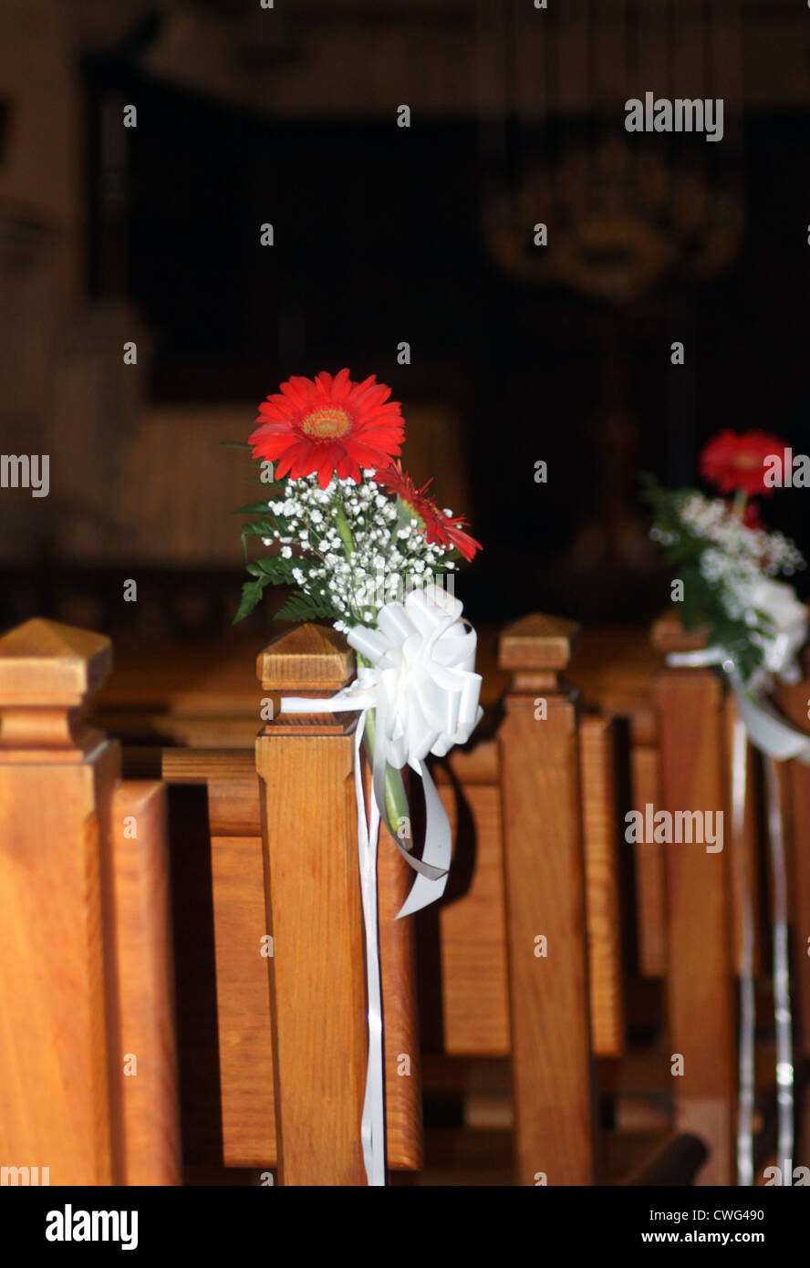 Bouquet of flowers in church with wooden pews receding into distance. Stock Photo