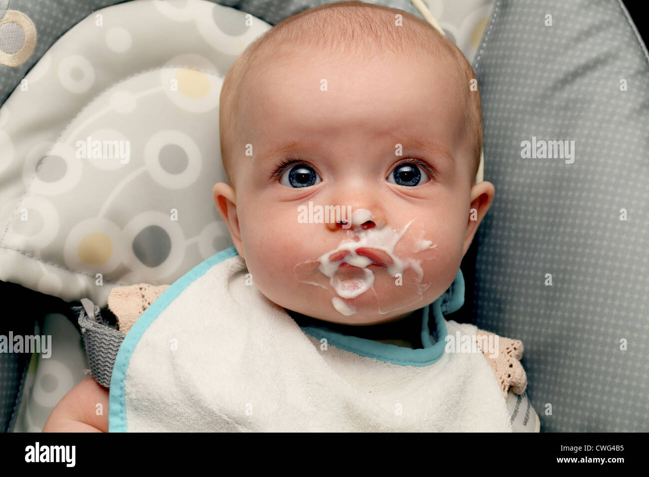A 6 month old baby girl with food round her mouth Stock Photo