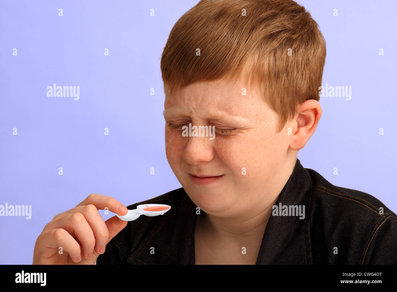 A 12 year old boy showing his dislike for the medicine he is about to take Stock Photo