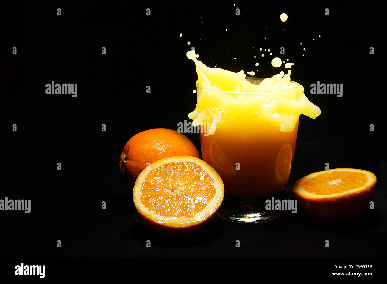Orange juice splash on black background Stock Photo - Alamy