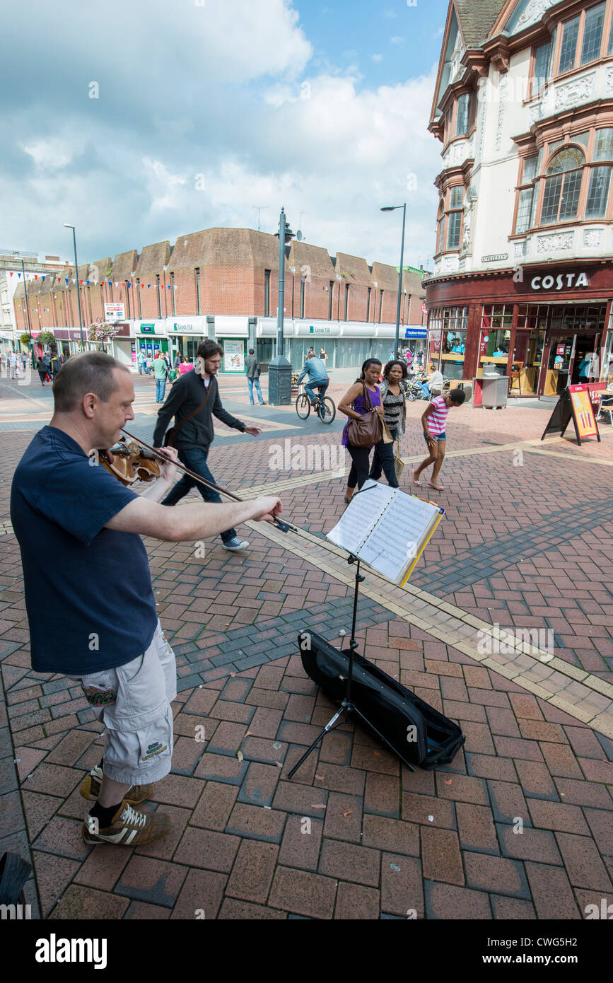 A busker playing a violin outside Costa Coffee on Derby's pedestrianised St Peter's Street. Stock Photo