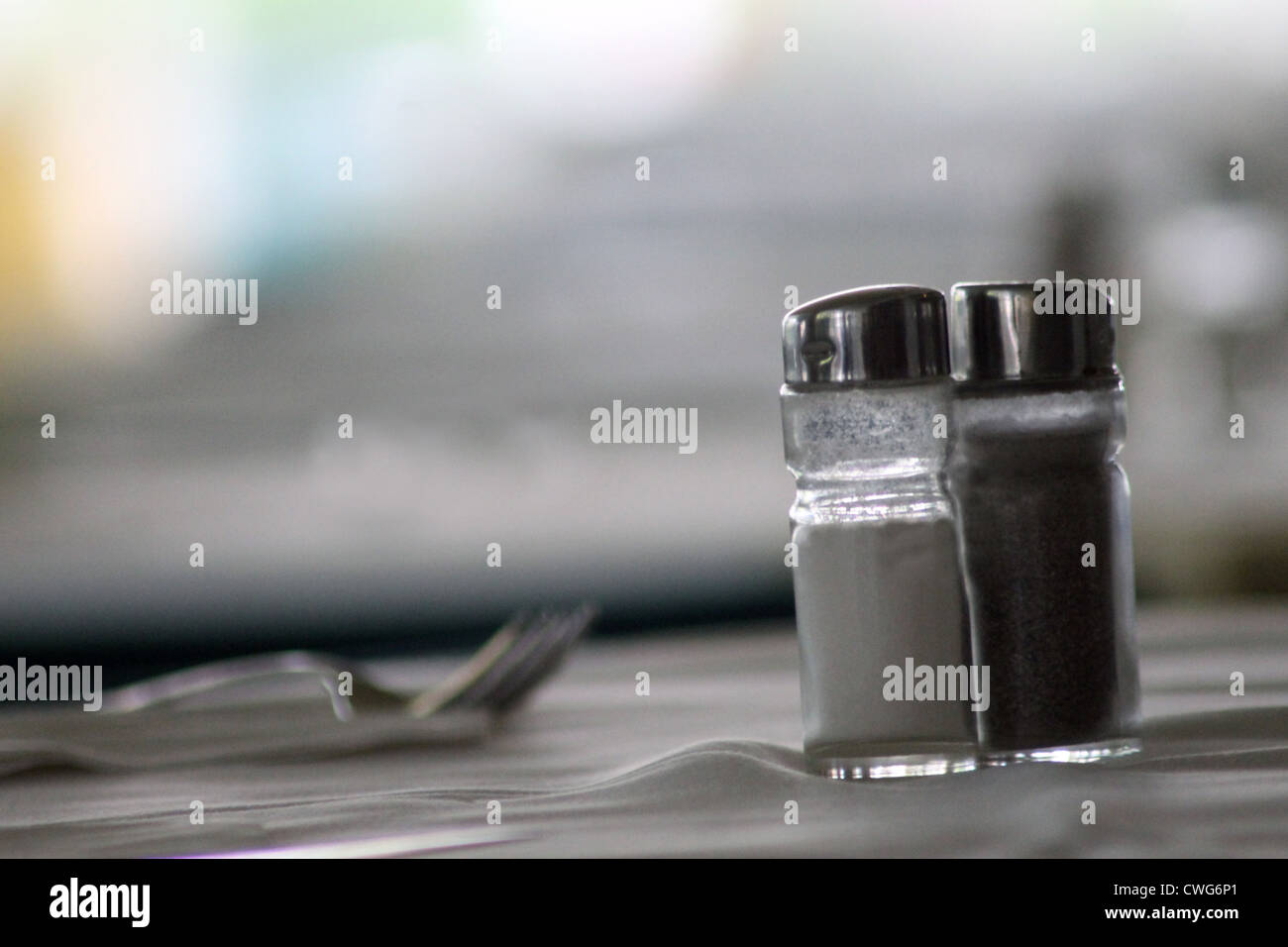 Salt and pepper shakers on table with fork and copy space, food and drink concept. Stock Photo