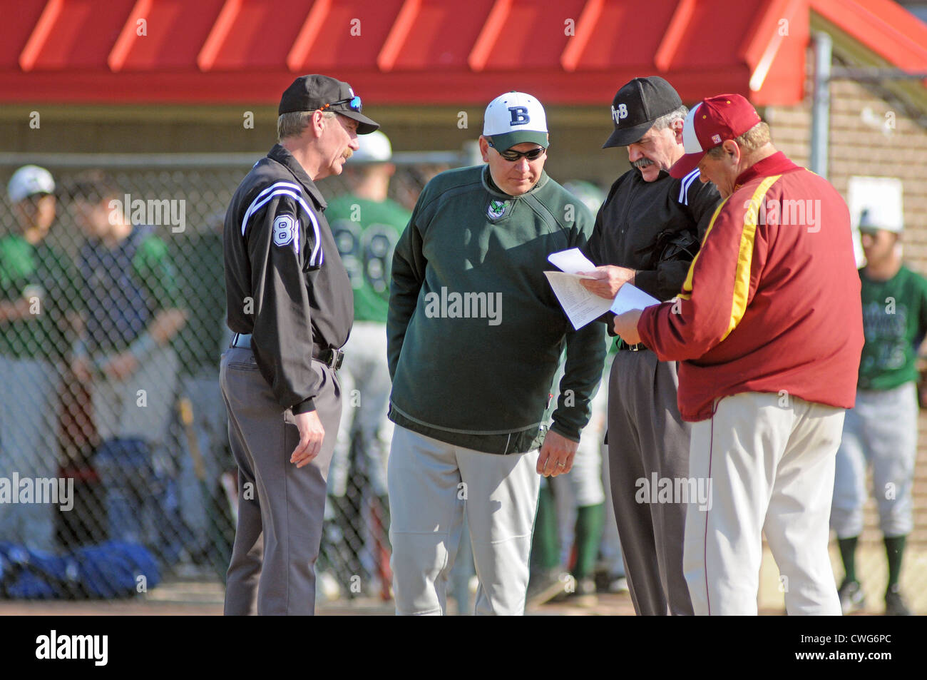 Baseball coaches and umpires exchange batting orders and go over ground rules prior to the start of a high school baseball game. USA. Stock Photo