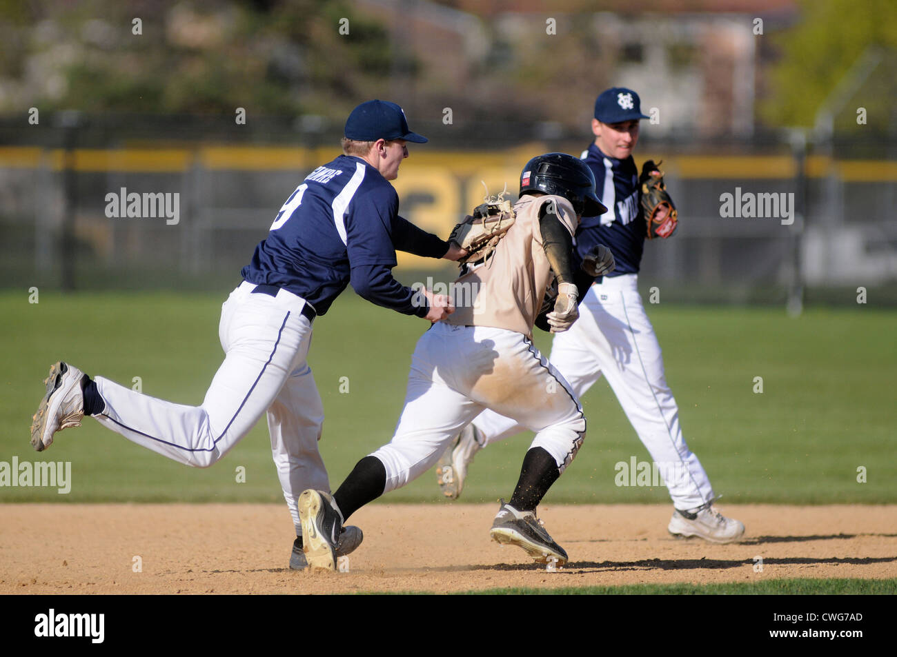 Baseball third baseman tags base runner between second and third base high school baseball game. USA. Stock Photo