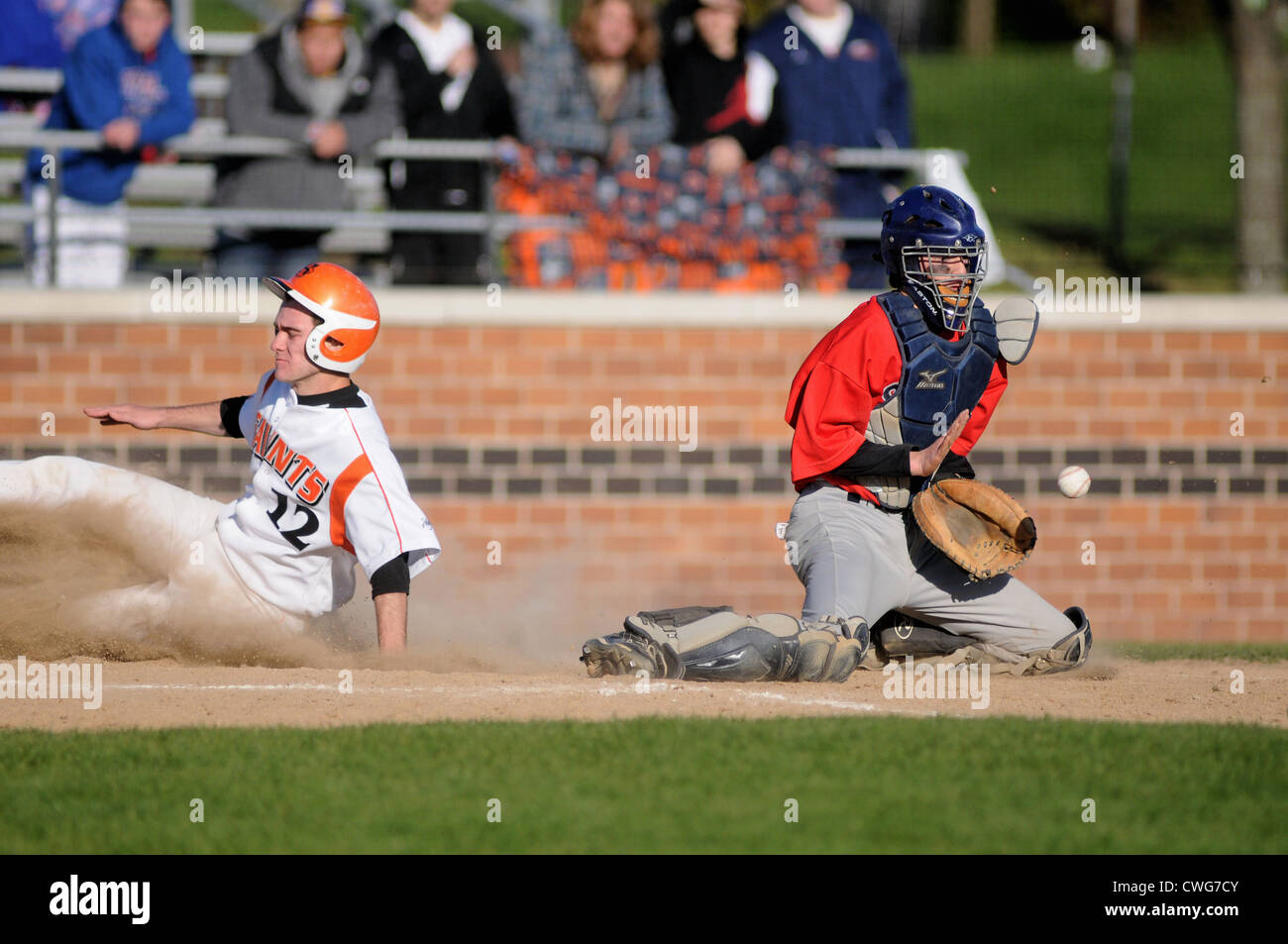 A base runner scores ahead of a throw home from the outfield as the
