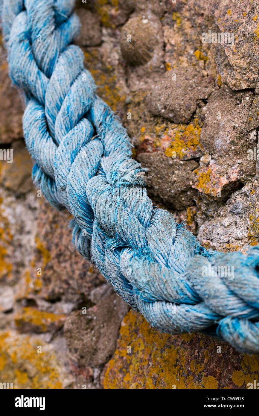 Old rope hanging on a harbour wall. Stock Photo