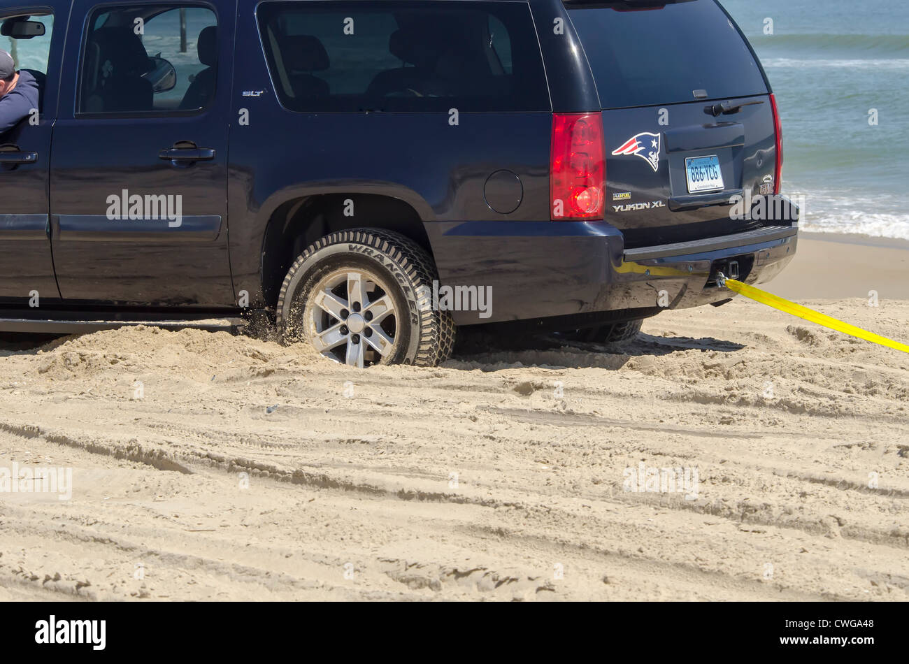 Four wheel drive vehicle stuck in sand on beach and being towed out