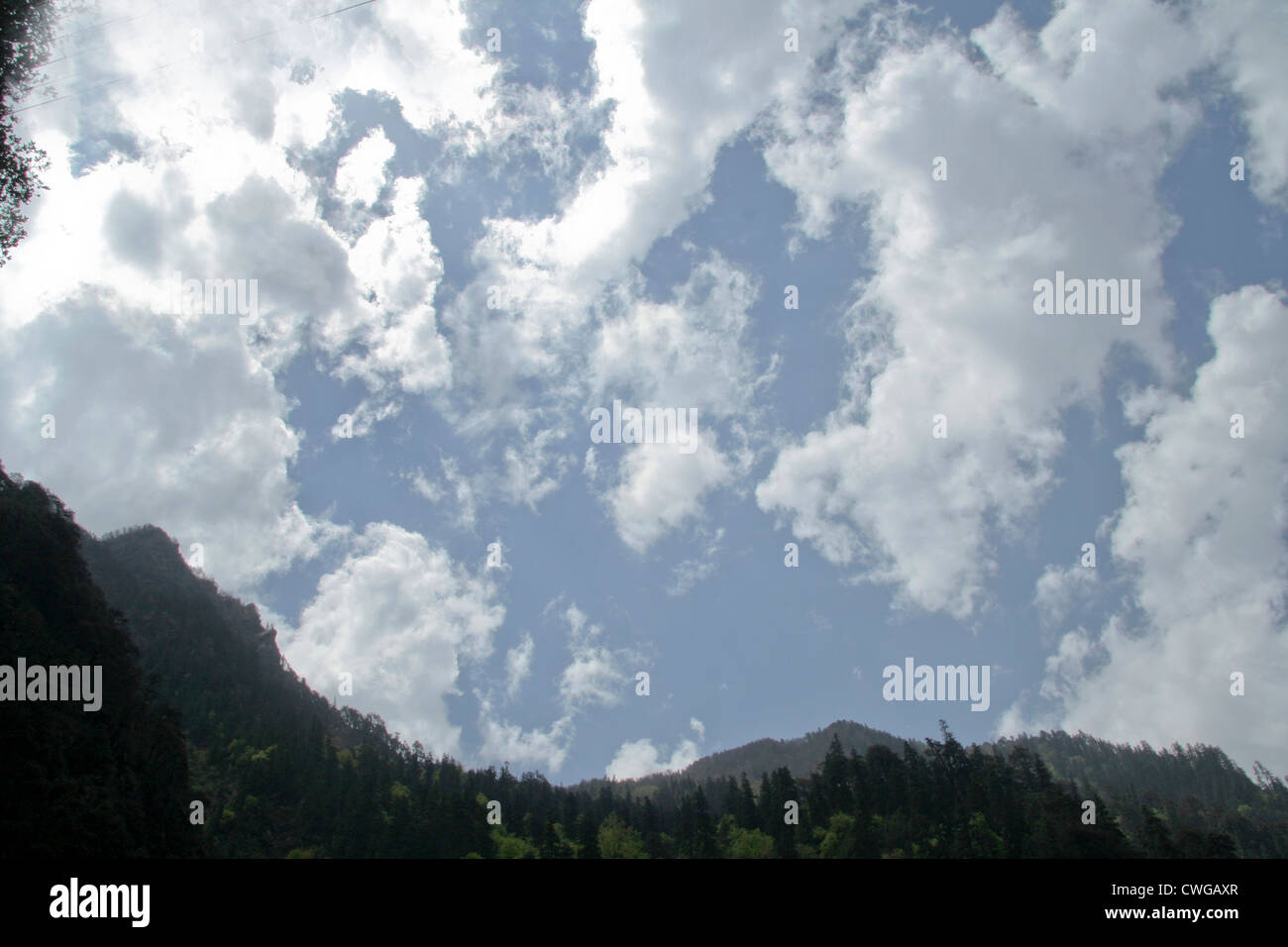Bright dazzling clouds with dark mountain in foreground Stock Photo