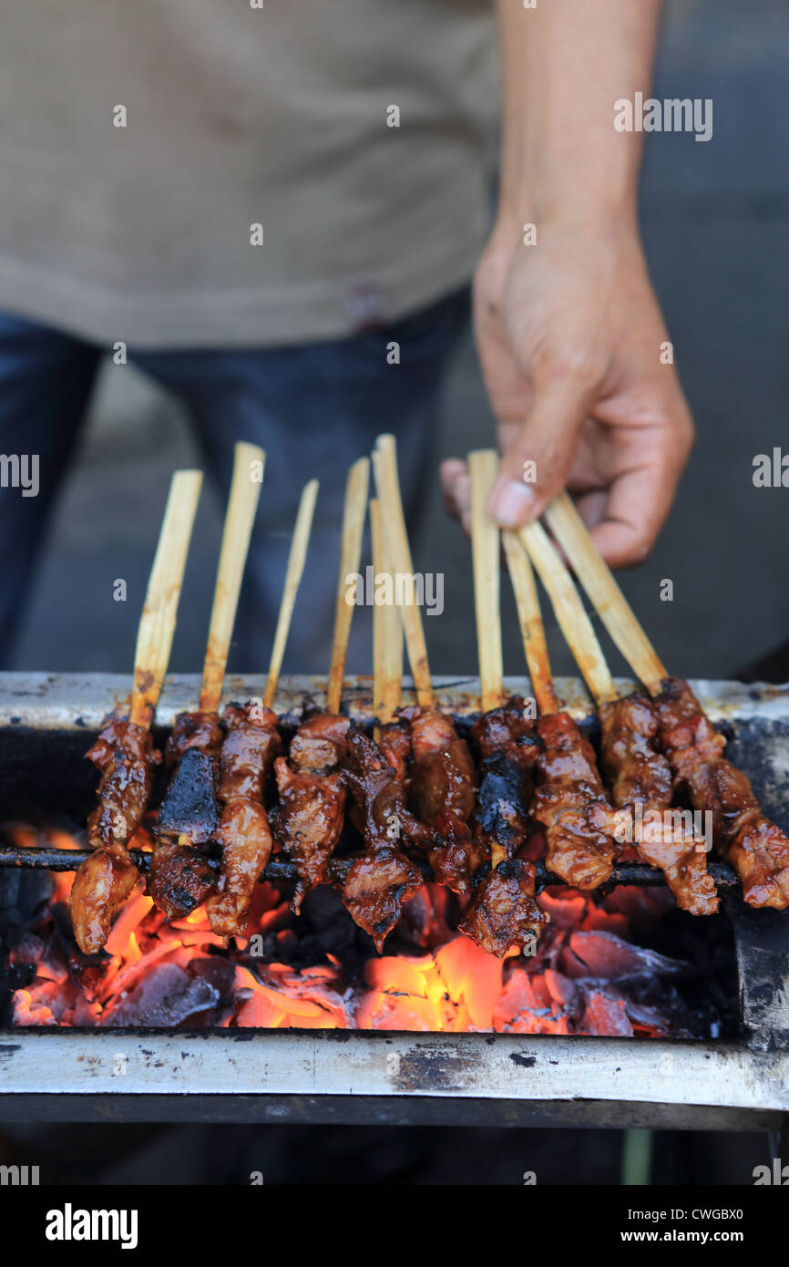 A vendor prepares sate chicken kebabs on the street in Jakarta, Java. Stock Photo