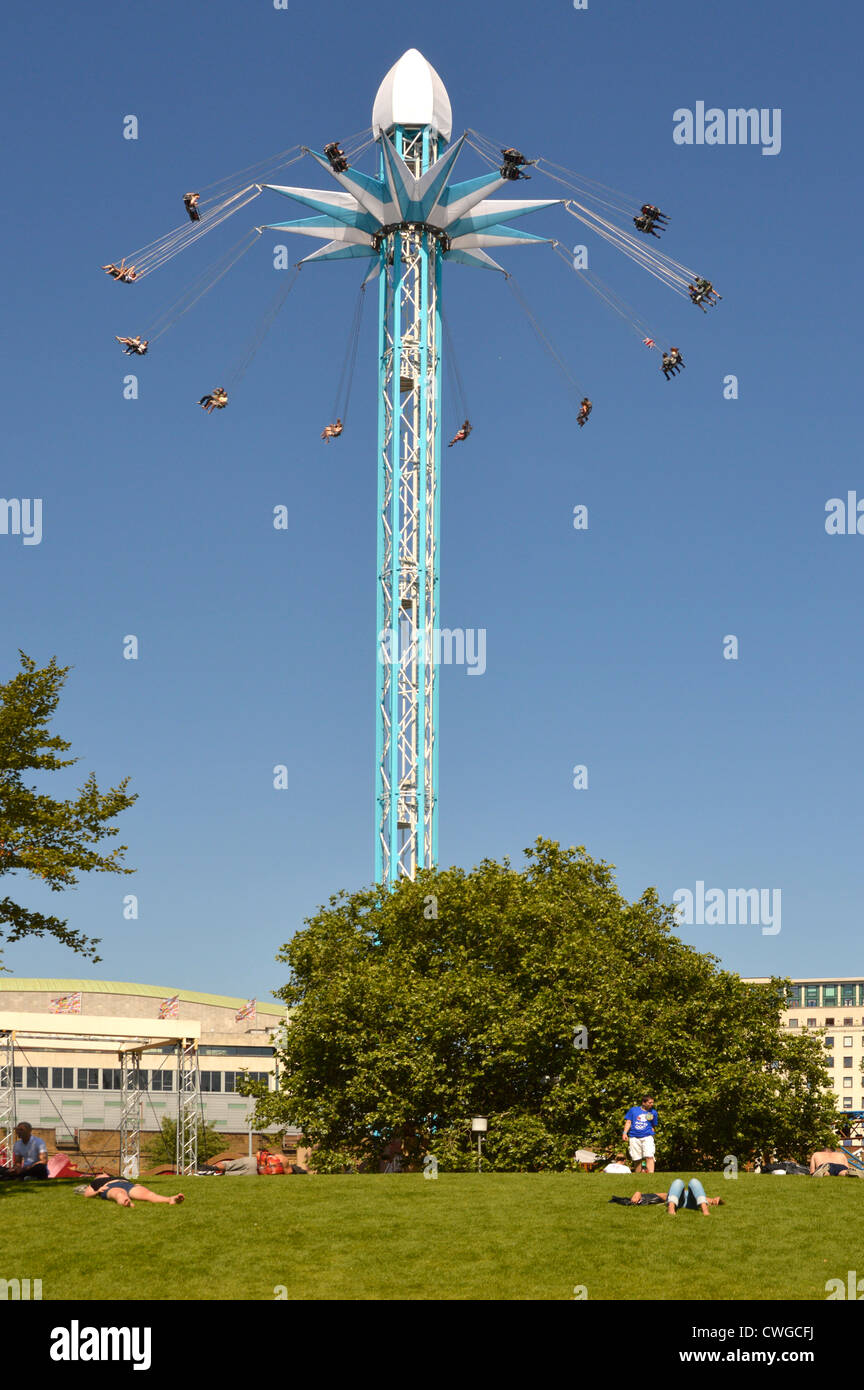 People relaxing in Jubilee Gardens with Star Flyer chair ride beyond ...