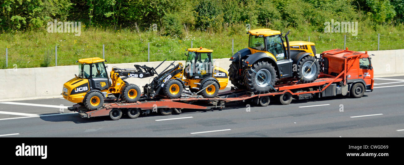 Three new JCB machines being transported on low loader Stock Photo